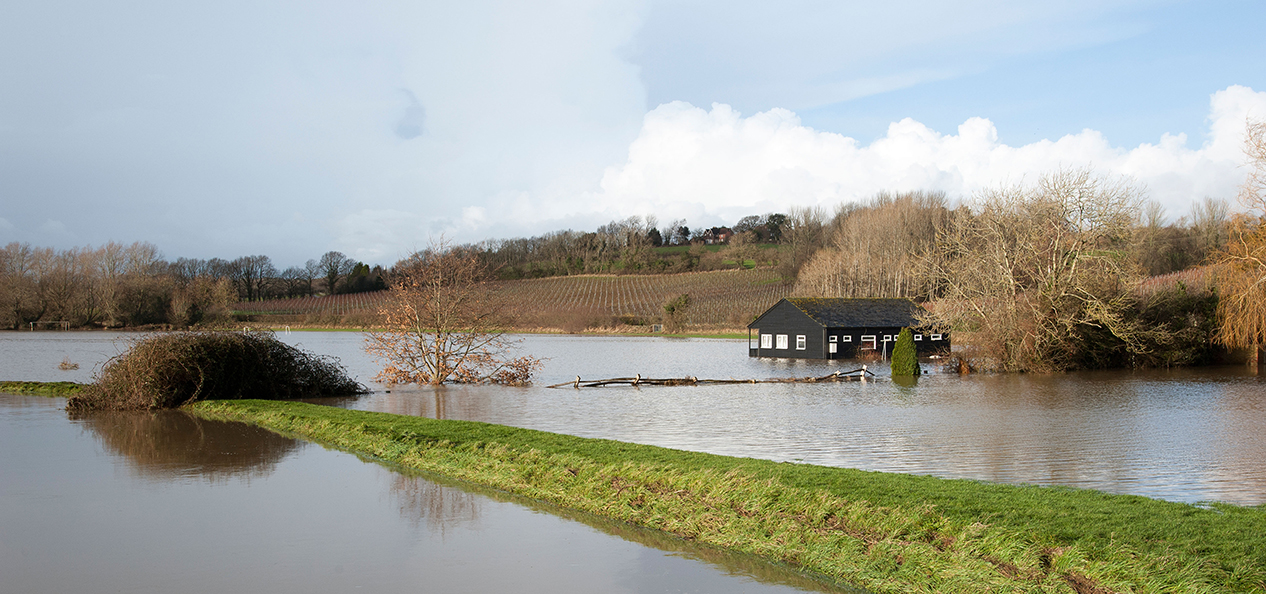 A flooded cricket pitch and pavilion after a river burst its banks.