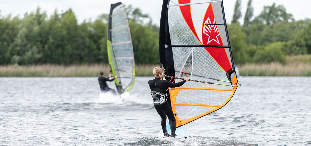 A man and a woman practice surf on a lake